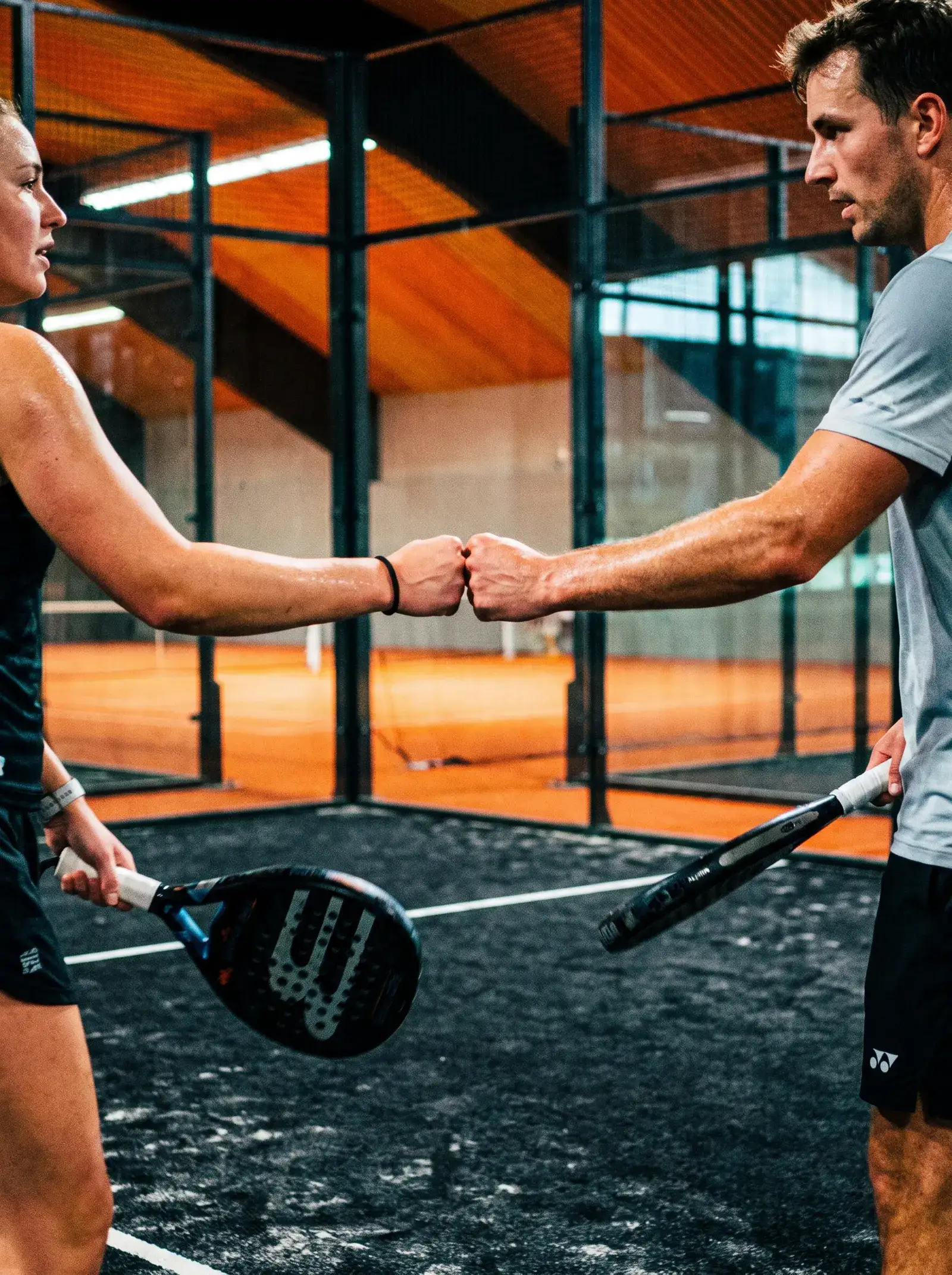 Zwei Padel-Spieler begrüßen sich mit einer Faust am Netz